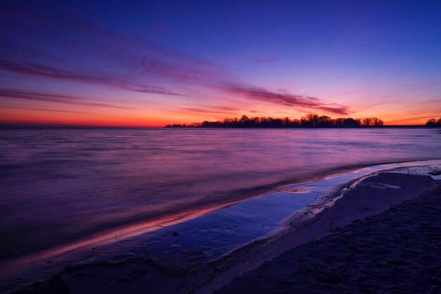 Beach against red fiery sunset. Sunrise and sea