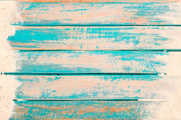 Beach background - top view of beach sand on old wood plank in blue sea paint background.