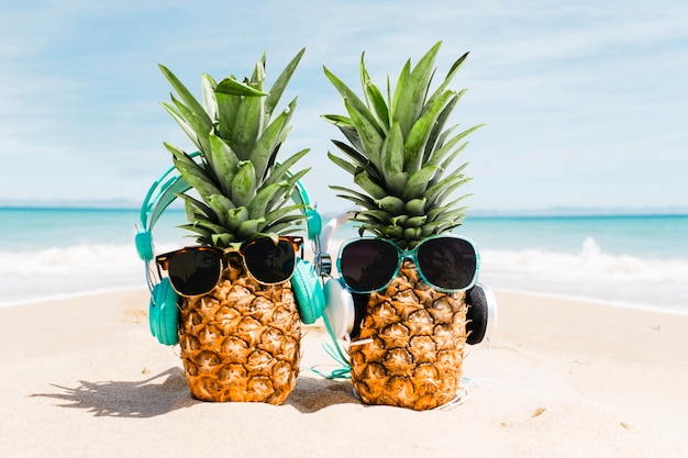 Beach background with pineapples wearing sunglasses