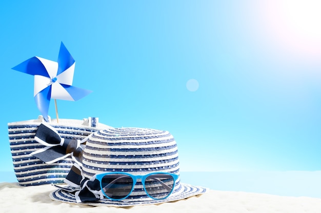 Beach bag with leisure accessories and hat on the sandy beach