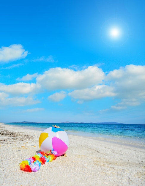 Beach ball with hawaiian necklace under a bright sun