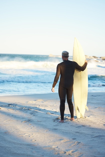 Beach board and man surfing on holiday for travel and adventure by the water in Hawaii Back of surfer by the ocean for the waves and freedom of summer on sea vacation on an island in nature