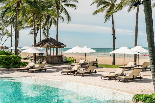 beach chair around swimming pool in hotel resort with sea beach