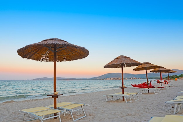 Beach chairs and parasols in Alghero at dawn