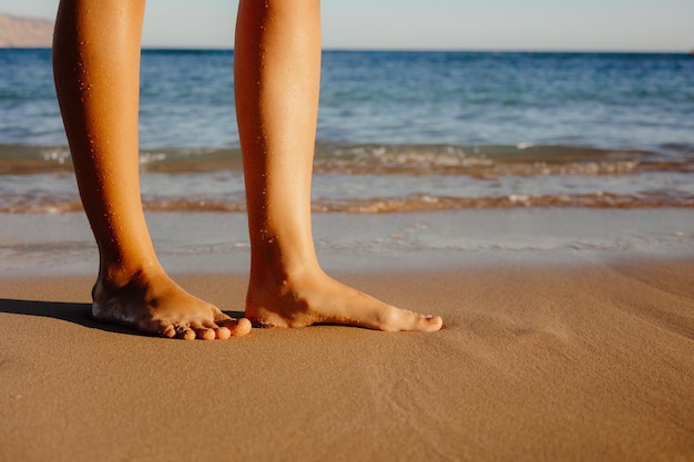 Beach feet close up barefoot woman walking in ocean water waves .