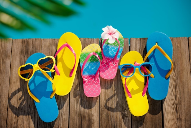 Beach flipflops and sunglasses on wooden planks near swimming pool