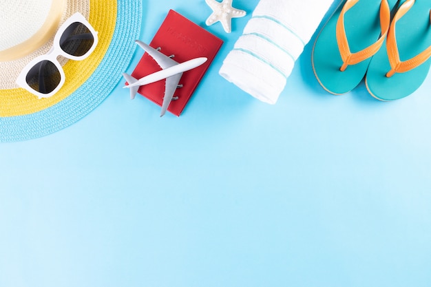 Beach hat, sunglasses, towel, passport, flip flops on light blue background. Summer or vacation.