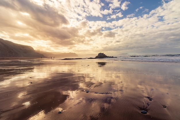 Beach and sea landscape with rocks, reflections in the sand, very cloudy sky with intense fog. Sopelana. Basque Country.
