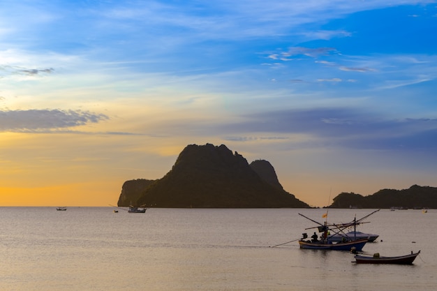 Beach, sea during the summer season in the morning sunrise with silhouette fishing boat.