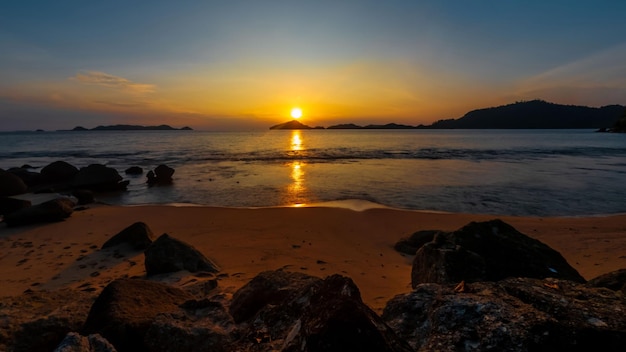 A beach at sunset with the sun setting behind it