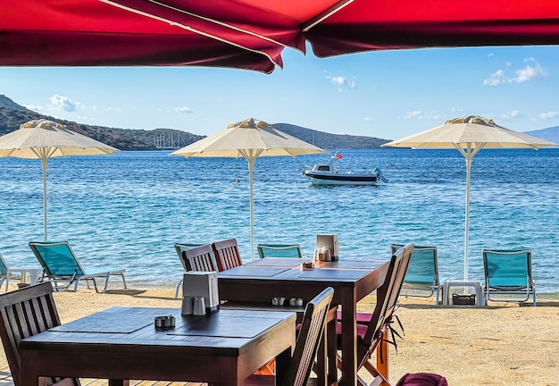 Beach umbrellas sun loungers tables and chairs on the shore of blue sea bay Summer vacation concept