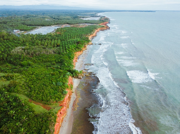 Beach view from the air with beautiful blue sea and beautiful green forest on Indonesian coast