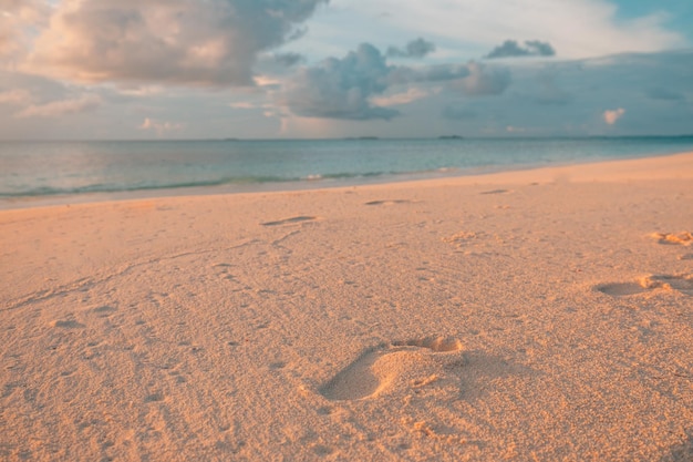 Beach wave and footsteps at sunset time Inspirational nature scenery with people Serene concept