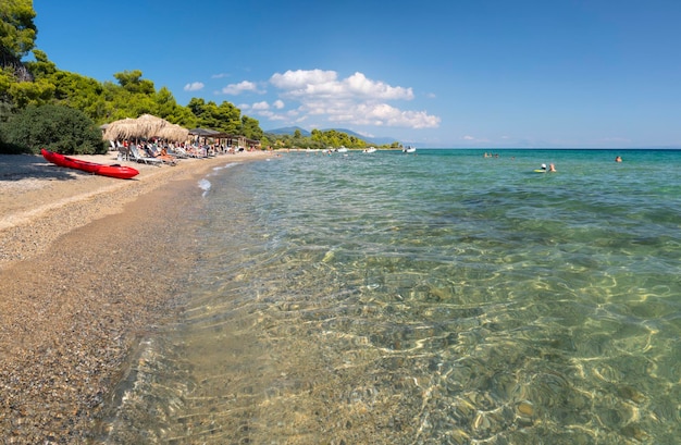 Beach with beach bar and tourists on the Aegean Sea in Greece