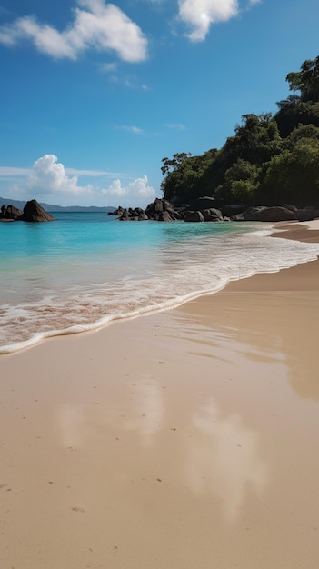 A beach with a blue sky and the water and the beach is surrounded by rocks.