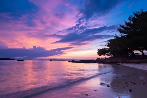 A beach with a purple sky and the sun reflecting on the water