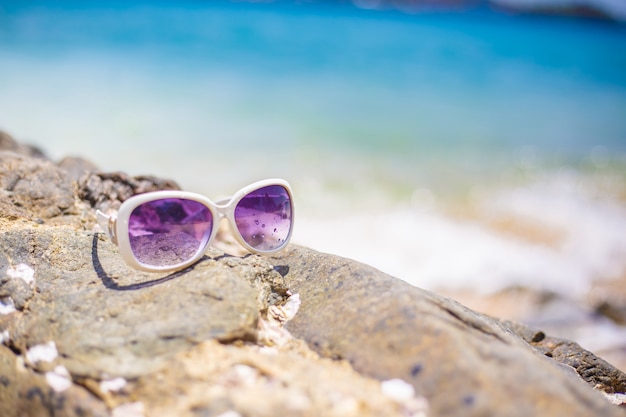 The beach with sunglasses and sandal on the rock, Copy space for text. Concept of summer.