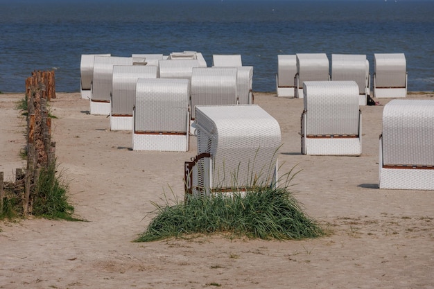 Photo a beach with white chairs and a blue water and a few white ones