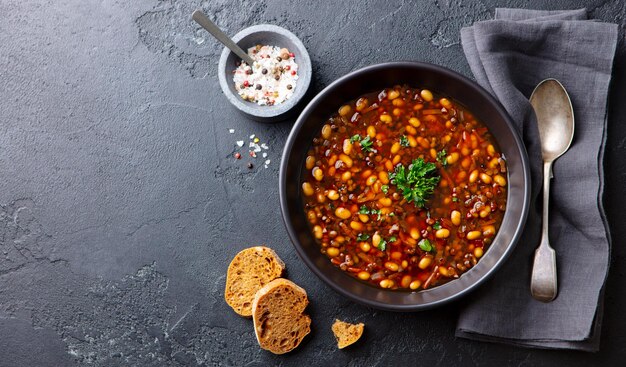 Photo bean soup in a black bowl grey background copy space top view