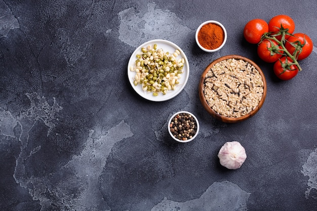 Bean sprouts rice vegetables and seasonings lie on a stone table