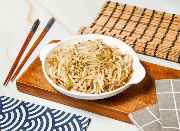 Bean sprouts with chopsticks served in dish isolated on wooden board and napkin side view of taiwan food