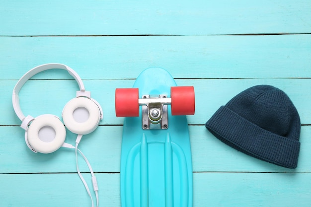 Beanie headphones and penny board on a blue wooden background Hipster accessories