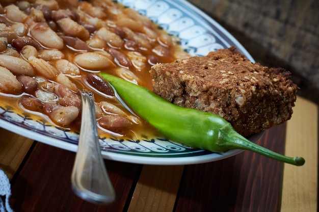 Beans with smoked pork on dinner plate with spelta bread and pepper on the plate