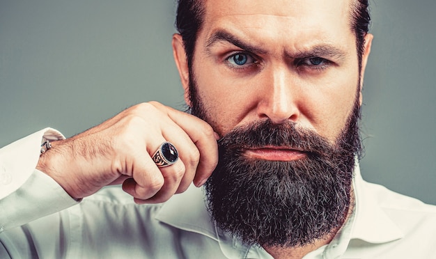 Beard is his style. Male with mustache growing. Portrait of bearded male in white shirt. Close up of handsome beard hipster elegant male. Bearded man close up.