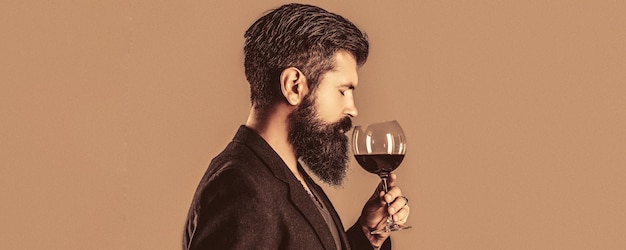 Beard man bearded sommelier tasting red wine Man with a glass of red wine in his hands Sommelier degustator with glass of wine winery male winemaker