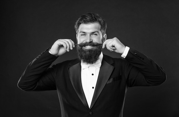 Bearded bridegroom in tuxedo on black background menswear