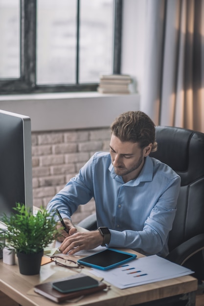 Bearded businessman in blue shirt working under project