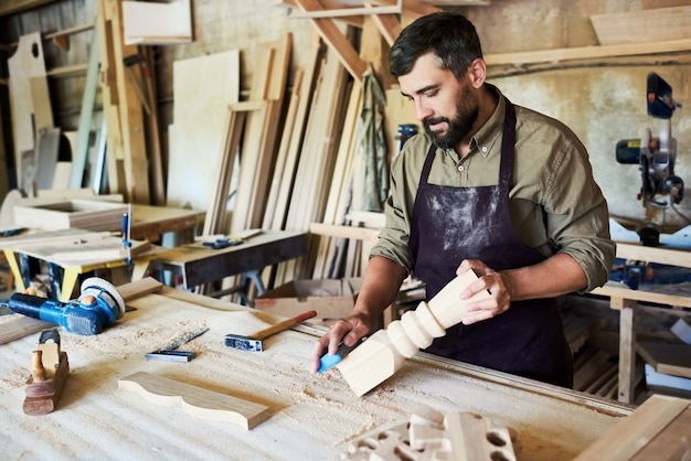 Bearded Carpenter Carving Stair Posts in Shop