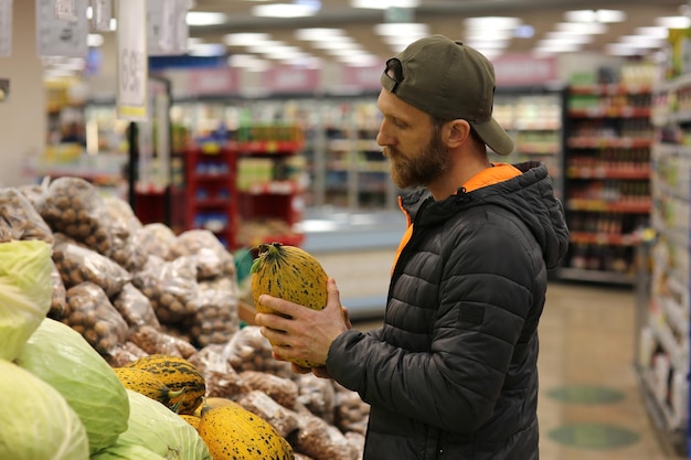 Bearded caucasian man customer selecting melons fruits in supermarket