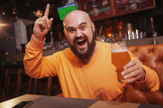 Bearded cheerful man celebrating victory of his favorite football team at sports bar