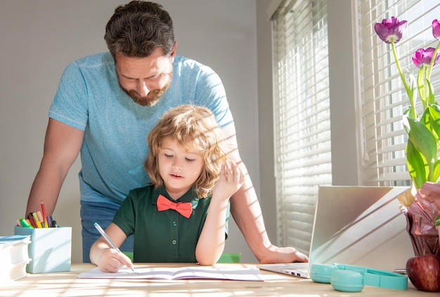 Bearded dad writing school homework with his kid son in classroom parenthood