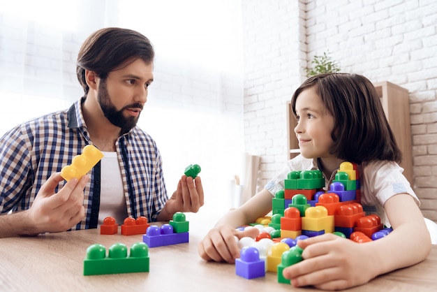 Bearded father asks son to share toy colored blocks.