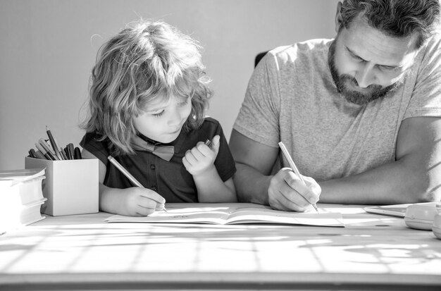 Photo bearded father writing school homework with his child son in classroom back to school