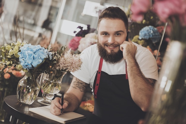 Bearded florist takes an order by mobile phone