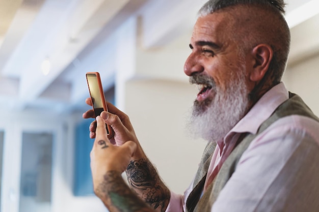 Bearded hipster mature man showing content on smartphone - side view - focus on cellphone screen