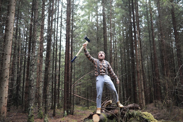 A bearded lumberjack with a large ax examines the tree before felling