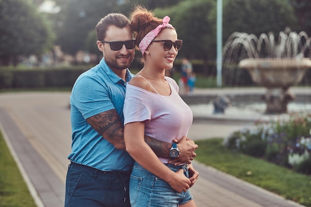 Bearded male hugs his beautiful redhead wife while standing in the park. Happy middle age couple during dating outdoors.