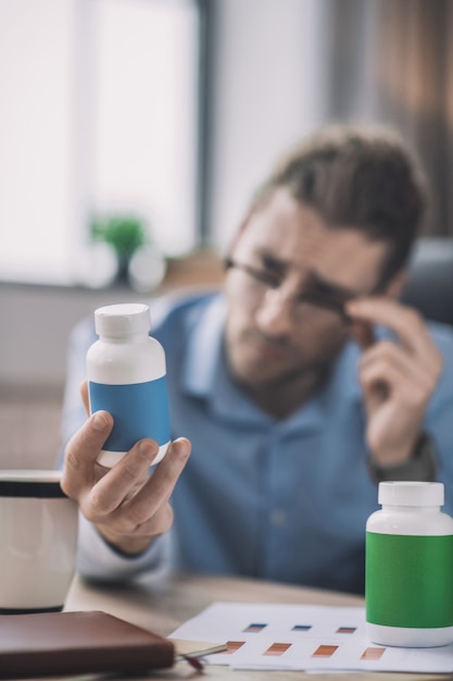 Bearded man in blue shirt reading about vitamins