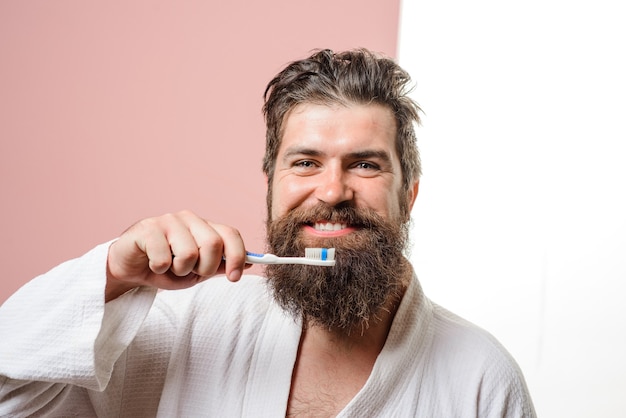 Bearded man brushing teeth with toothbrush dental higiene oral care smiling young man with