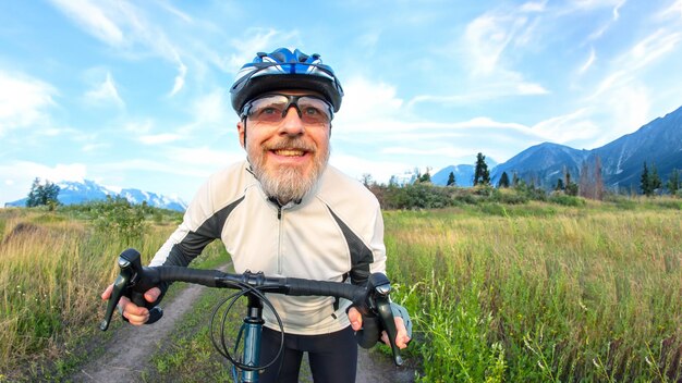 bearded man cyclist rides a bike on a road in nature sports hobbies and entertainment for health