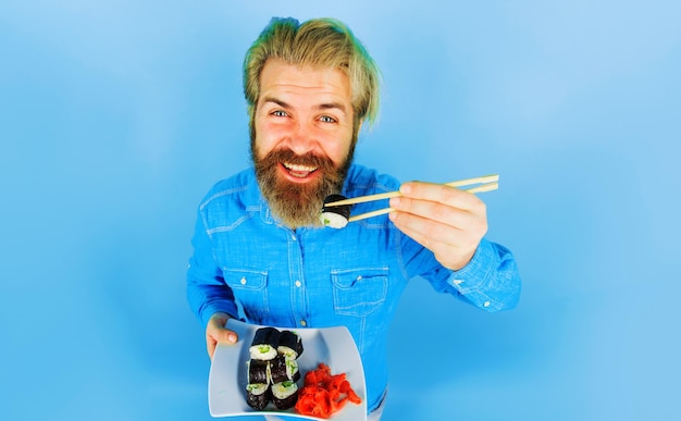 Bearded man eat sushi roll handsome guy with pickled ginger and sushi roll on plate japanese food