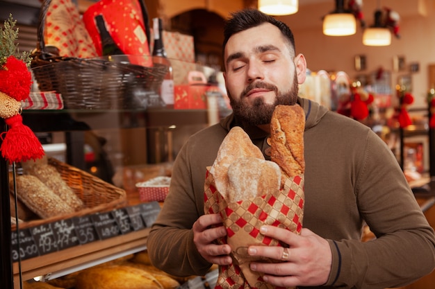 Bearded man enjoying smell of delicious freshly baked bread.