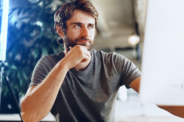 Bearded man freelancer using computer in a modern coworking place. Freelance business concept