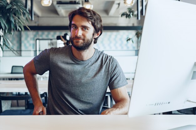 Bearded man freelancer using computer in a modern coworking place. Freelance business concept