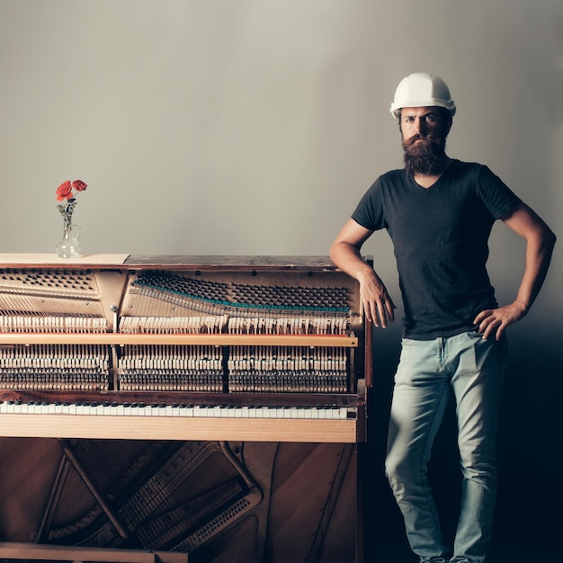 Bearded man in helmet near wood piano