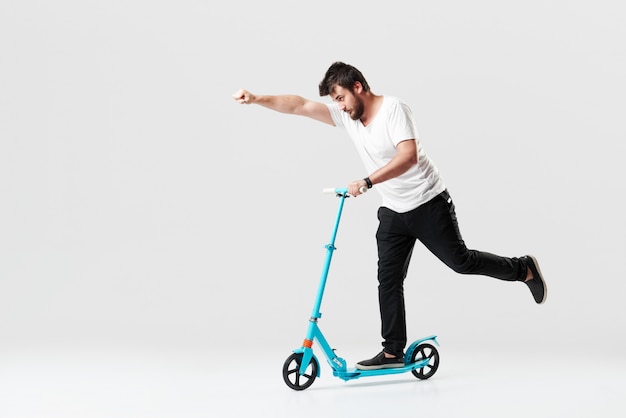 Photo bearded man holding the electric scooter and riding it while feeling delighted